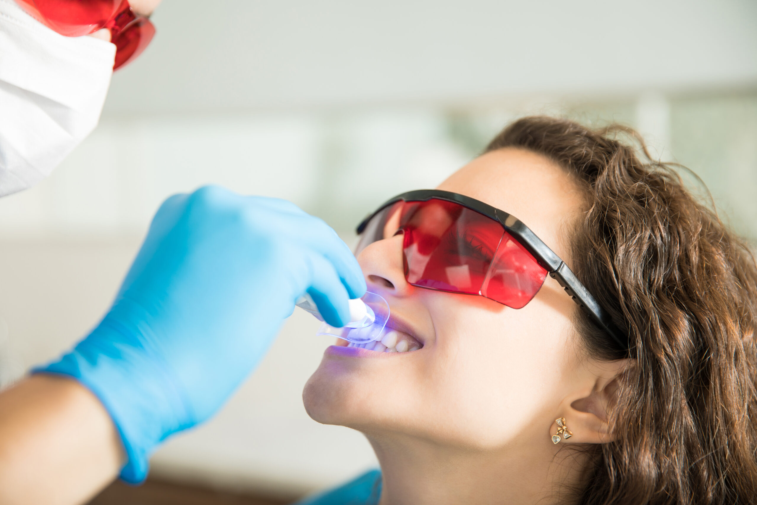 woman having dental checkup with ultraviolet light